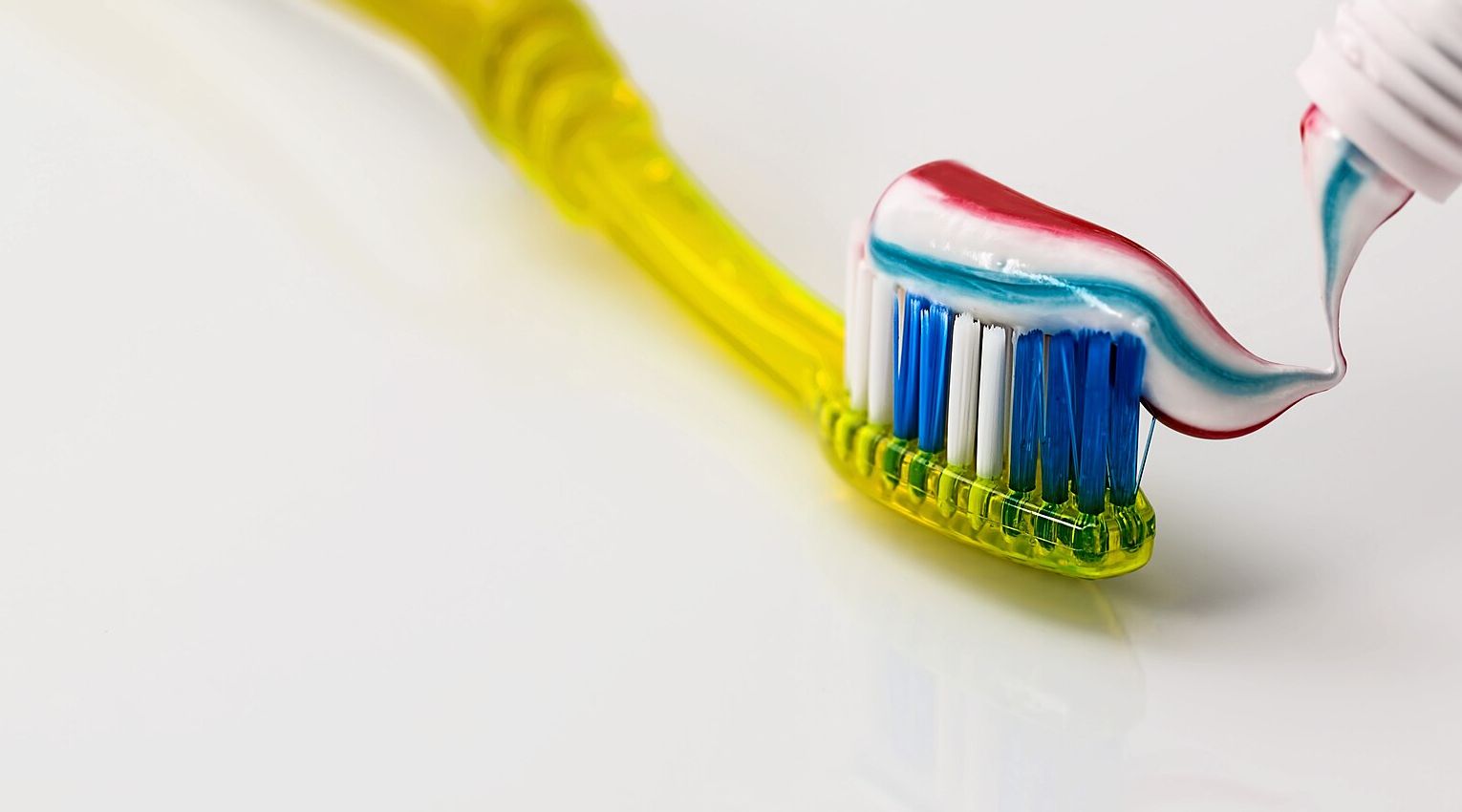 Toothpaste being squeezed onto a toothbrush