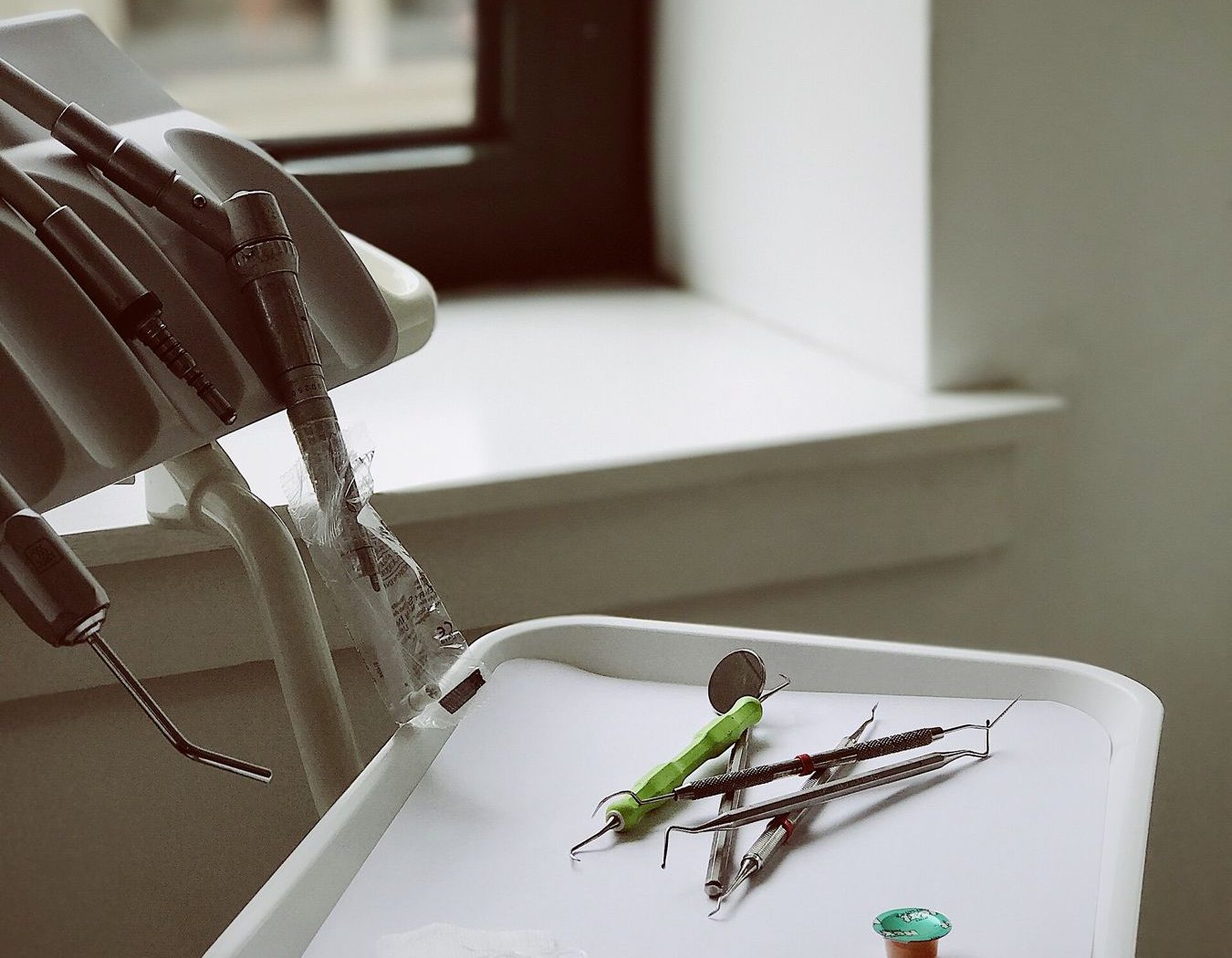 Dental instruments laid out on a tray beside a window